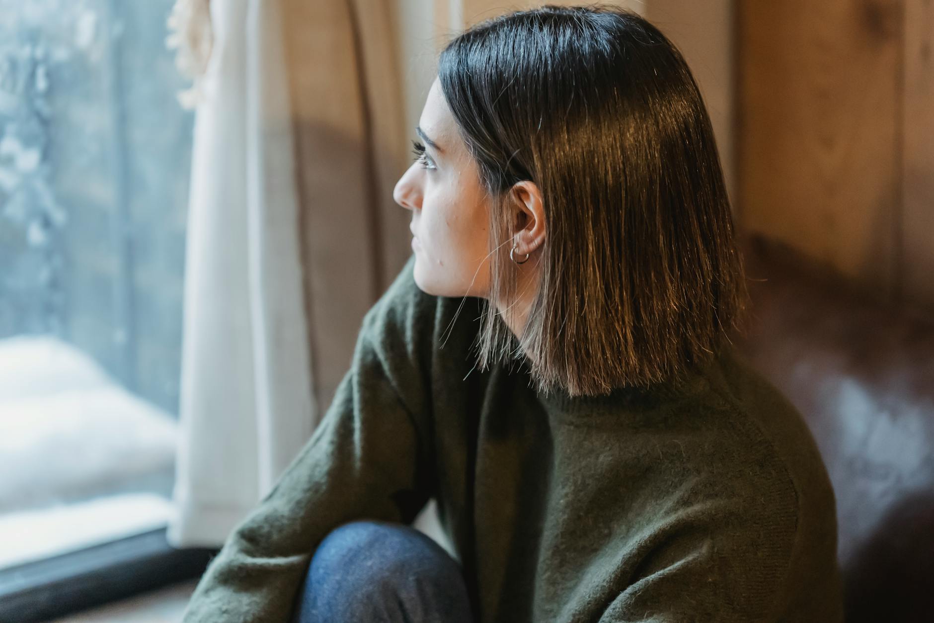 thoughtful woman sitting on windowsill in solitude