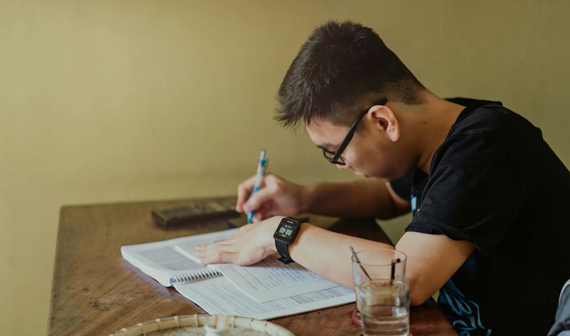 man in black shirt sitting and writing