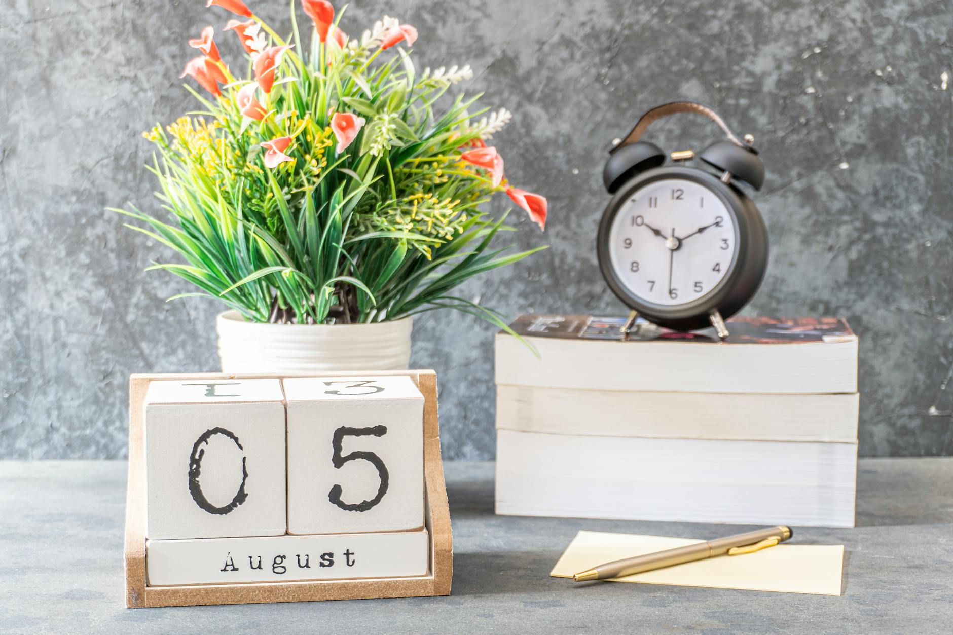 close up shot of a black alarm clock beside a calendar